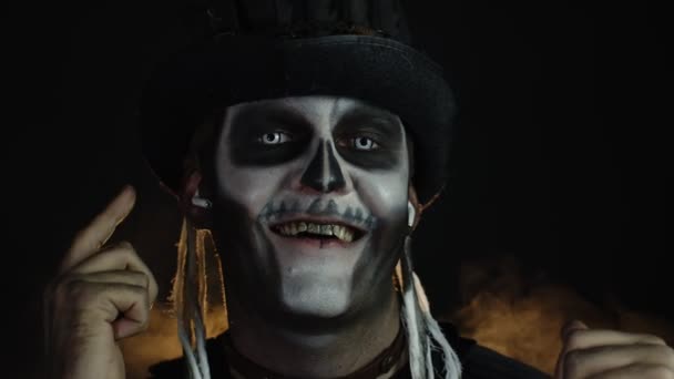 Hombre espeluznante con esqueleto de maquillaje en sombrero de copa. Tipo usando auriculares, escuchando música, bailando - Metraje, vídeo