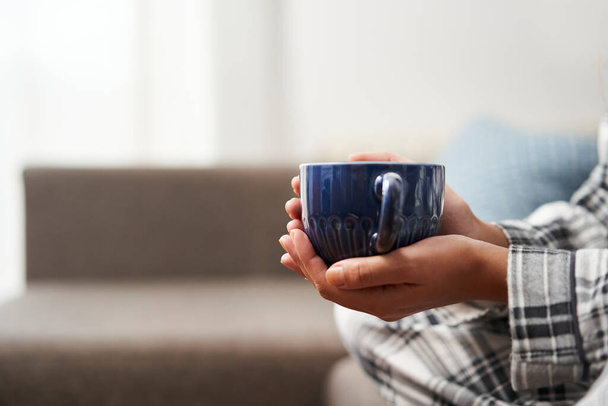 Feche a foto da mão da mulher segurando um café. Relaxamento em casa conceito. - Foto, Imagem