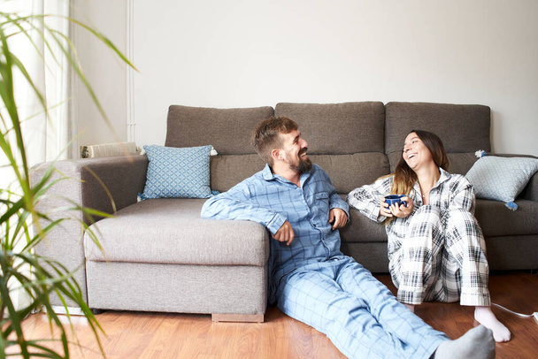 若いカップルは家でパジャマを着ていた。彼らは一緒にいることを楽しんで、休日に満足して笑っています. - 写真・画像