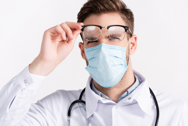 Portrait of doctor with medical mask looking at steamed eyeglasses isolated on white - Photo, Image