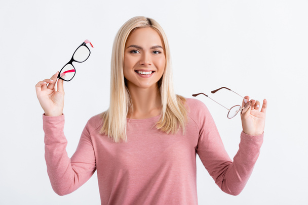 Positive woman looking at camera while holding eyeglasses isolated on grey - Foto, Imagen