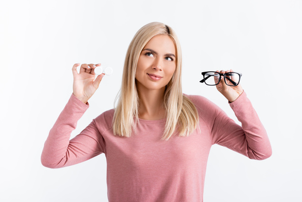 Σκεπτική γυναίκα που κρατά γυαλιά και περιέκτη με φακούς επαφής που απομονώνονται σε λευκό - Φωτογραφία, εικόνα