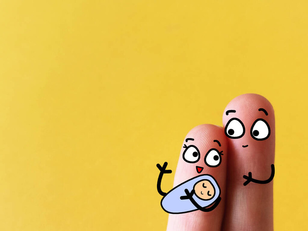 Deux doigts sont décorés comme un couple tenant un bébé mignon. - Photo, image