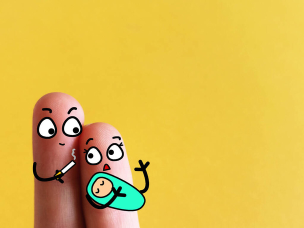 Dois dedos são decorados como um casal segurando um bebê bonito. A mãe está com raiva do pai enquanto fuma cigarro perto do bebê. - Foto, Imagem
