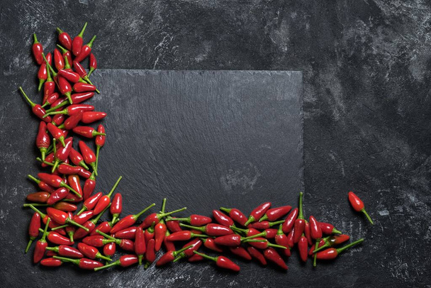Red hot chilli papričky úhel rám na černém stole a černý rock sekání stůl, horní pohled s kopírovacím prostorem pro váš kulinářský text. - Fotografie, Obrázek