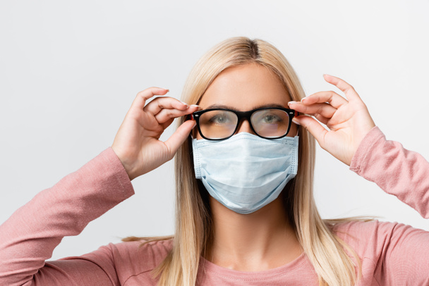 Young woman in medical mask holding misted eyeglasses isolated on grey - Foto, Bild