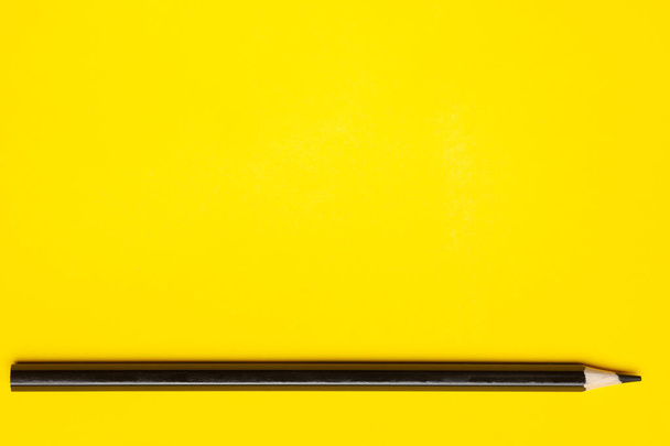 horizontal black sharp wooden pencil on a bright yellow background, isolated, copy space, mock up - Φωτογραφία, εικόνα