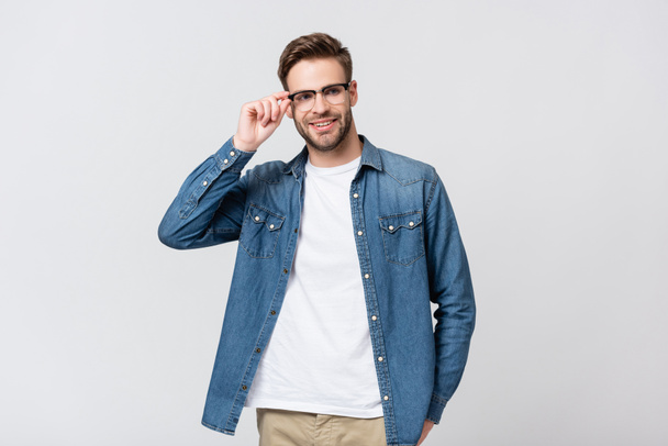 Mosolygó férfi megérinti szemüveg elszigetelt szürke - Fotó, kép