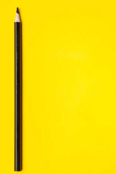 vertical black sharp wooden pencil on a bright yellow background, isolated, copy space, mock up - Fotografie, Obrázek