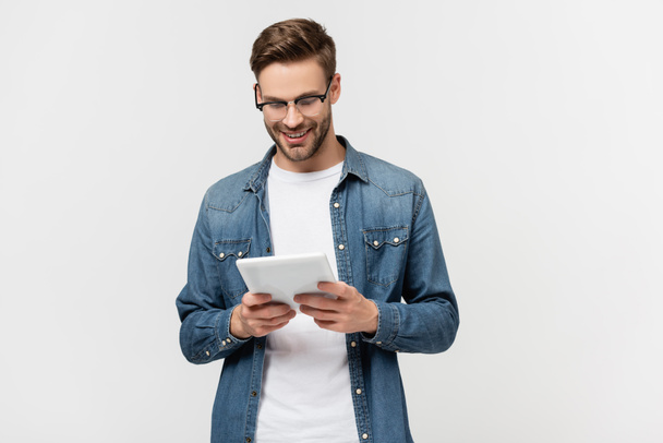 Homem sorridente em óculos segurando tablet digital isolado em cinza - Foto, Imagem