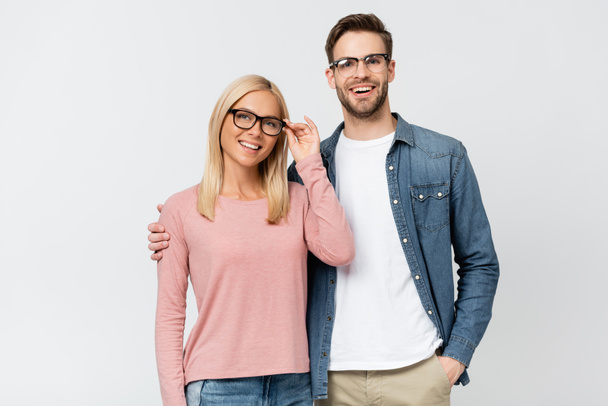 Smiling man in eyeglasses embracing girlfriend isolated on grey - Photo, Image
