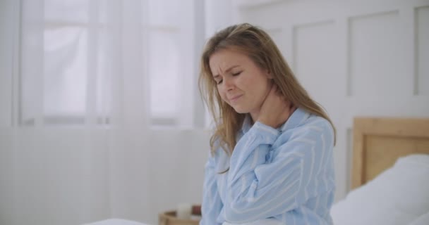 jonge vrouw ligt in bed in de ochtend voelt pijn in de nek na nacht slaap, wakker met pijnlijke plotselinge pijn of stijfheid, onjuiste houding tijdens de slaap. Fibromyalgie-concept - Video