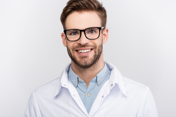 Médico sonriente en anteojos mirando a la cámara aislada en gris  - Foto, Imagen