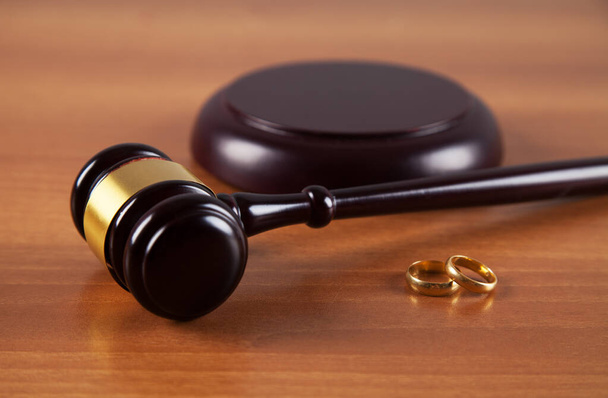 Hammer of a judge, a pair of wedding rings on a wooden background. Family law. Divorce.  - Photo, Image
