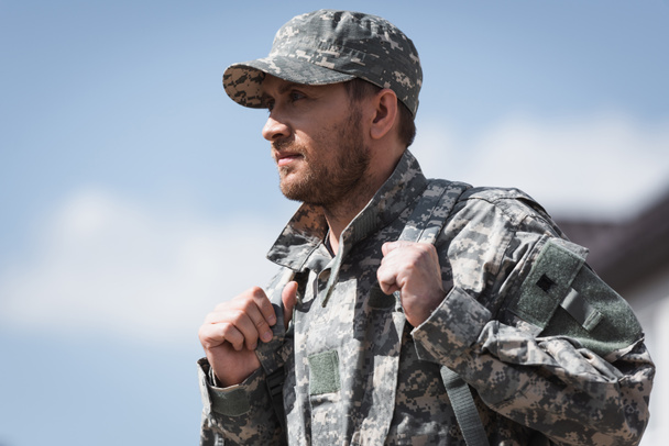 Aikuinen sotilas univormussa reppu katselee pois hämärtyneellä taustalla - Valokuva, kuva