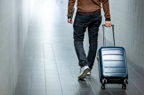 Koncepcja ubezpieczenia podróży. mężczyzna turysta przewożący bagaż walizkowy i cyfrowy tablet spaceru w terminalu lotniska. - Zdjęcie, obraz