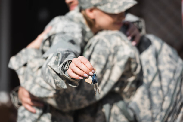 Klíče s rozmazané vojenské manželky a manžela objímající na pozadí - Fotografie, Obrázek