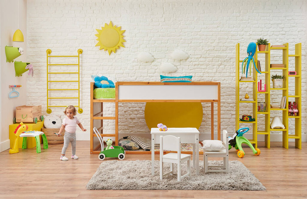 Modern ahşap bebek odası, çocuk, dekoratif merdivenler ve ranza, masa ve çocuk tarzı. Oyuncak, beyaz tuğla duvar güneşi ve bulut aksesuarları. - Fotoğraf, Görsel