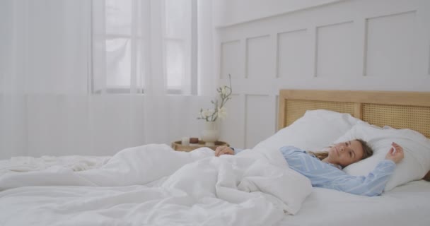 Happy beautiful woman wake up, smiling and stretching her arms in her bed in the bedroom. Young female use relax time at home. Lifestyle woman at home concept. - Footage, Video