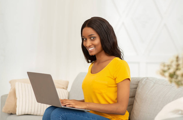 Positive black businesswoman using laptop for distance work, education or communication at home - Foto, Imagen