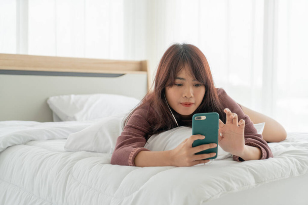 beautiful Asian women playing smartphone on bed - 写真・画像