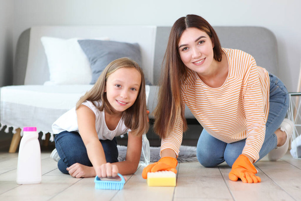 Anya és lánya jó hangulatban vannak, fertőtlenítőszerekkel és mosószerekkel takarítják a házat. - Fotó, kép
