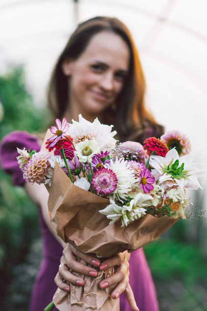The girl is holding a bouquet in her hands. The bouquet is in focus. Floral arrangement.  - Foto, Imagem