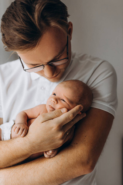 Handsome man with adorable newborn baby girl, caring dad gently hold little daughter in arms, enjoy tender parenting moments, smiling, fatherhood concept - Фото, изображение