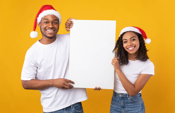 Африканская пара держит в студии пустой рождественский плакат - Фото, изображение