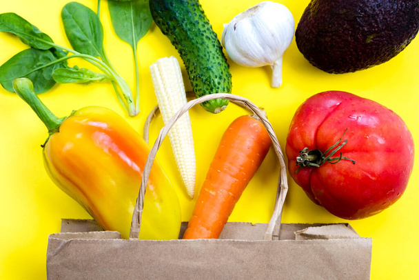 Concepto de entrega de verduras crudas orgánicas naturales de la tienda de comestibles, alimentos saludables desintoxicados, verduras en una bolsa de papel a la vista de color amarillo desde arriba, la disposición plana vegetal respetuoso del medio ambiente - Foto, imagen