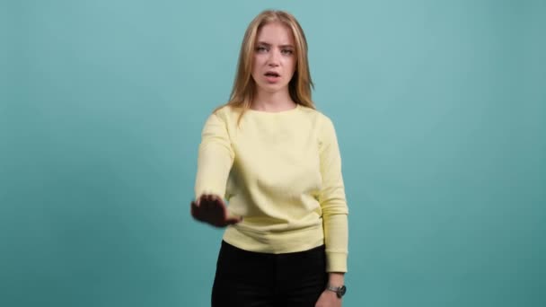 jonge vrouw maken stop gebaar met haar hand, geïsoleerd op een turquoise achtergrond. - Video