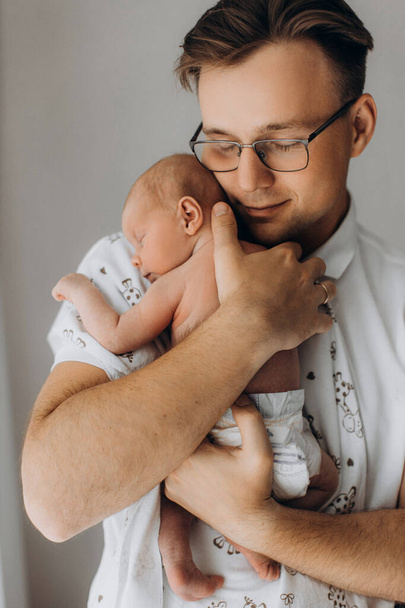 Handsome man with adorable newborn baby girl, caring dad gently hold little daughter in arms, enjoy tender parenting moments, smiling, fatherhood concept - Foto, Bild