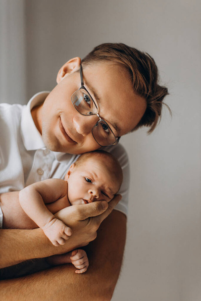 Caring father gently hold adorable newborn baby girl in arms, happy dad enjoy moments with little daughter, smiling, parenting and fatherhood concept - Foto, Imagen