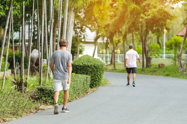Πλάτη άποψη πορτρέτο ενός ηλικιωμένου Ασιάτη σε καλή φυσική κατάσταση φορούν το περπάτημα και το τρέξιμο για την καλή υγεία στο δημόσιο πάρκο. Ανώτερος δρομέας στη φύση. Μεγαλύτερος άνθρωπος απολαμβάνει ειρηνική φύση. Έννοια υγειονομικής περίθαλψης. - Φωτογραφία, εικόνα
