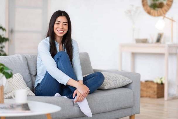 Portrait of relaxed smiling korean lady posing on sofa at home - Foto, imagen