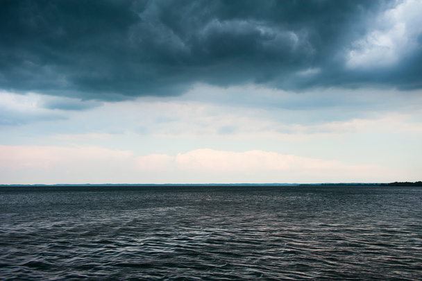 Stormy weather at lake with dark clouds - Фото, изображение
