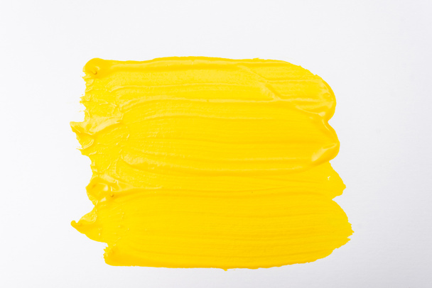 horní pohled na abstraktní barevné žluté tahy štětcem na bílém pozadí - Fotografie, Obrázek