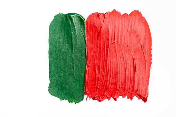 bovenaanzicht van abstracte kleurrijke groene en rode verf penseelstreken op witte achtergrond - Foto, afbeelding