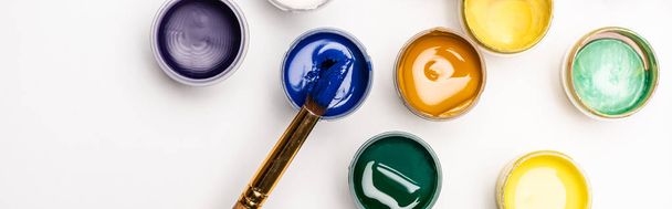 top view of colorful Gouache paints and paintbrush on white background, panoramic shot - 写真・画像