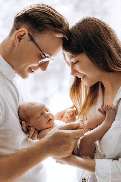 Happy young parents with newborn baby girl, loving mom hold little daughter in arms, caring dad gently hold a hand of adorable baby girl, tender family moments, parenting concept - Fotoğraf, Görsel