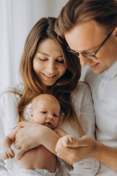 Happy parents with newborn baby, caring mother hold little daughter in arms, beautiful father gently hold hand of baby girl, smiling, enjoy happy moments, young family concept - Fotoğraf, Görsel