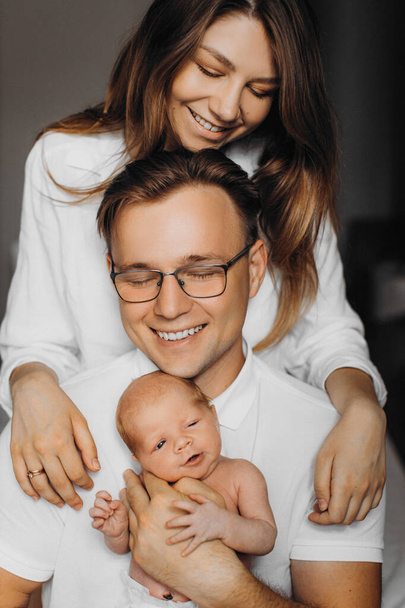 Overjoyed parents with newborn baby girl, loving dad gently hold little daughter in arms, beautiful mother hug caring father, smiling, enjoy happy moments, young family concept - Foto, Bild