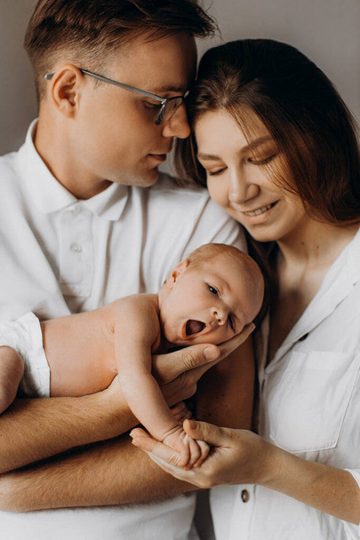 Caring parents with newborn baby, loving dad gently hold little daughter in arms, beautiful mother hold tiny hand of baby girl, smiling, enjoy happy moments, young family concept - Фото, зображення