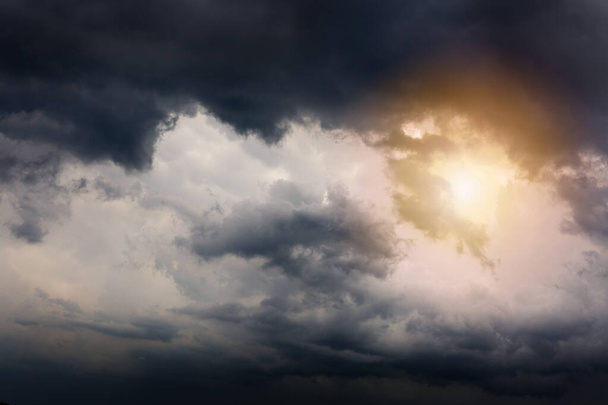Donker onheilspellende grijze stormwolken en zonlicht. Dramatische lucht. - Foto, afbeelding