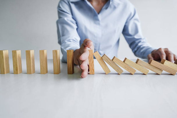 Risico en strategie in het bedrijfsleven, Close-up van de zakenvrouw hand stoppen houten blok tussen drie manieren van vallen in de lijn van domino. - Foto, afbeelding