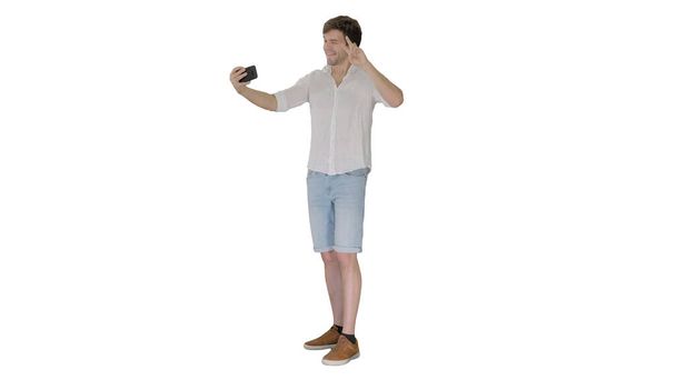 Young man in casual white shirt taking selfies on his phone on w - Фото, зображення