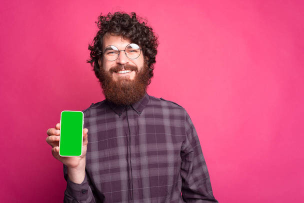Cheerful young man holding the phone and smiling at the camera - Photo, Image