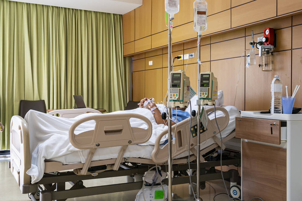 пацієнт спить на ліжку були оброблені сольовим розчином або проходить автоматичний інфузійний насос натрію, що висить на IV підставці для ліків або поживних речовин в кімнаті в лікарні
 - Фото, зображення