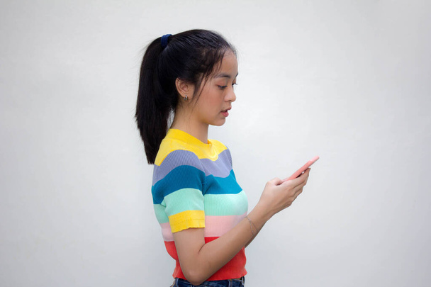 Азія тайський підліток кольорова футболка красива дівчина використовує свій телефон і посмішку
 - Фото, зображення