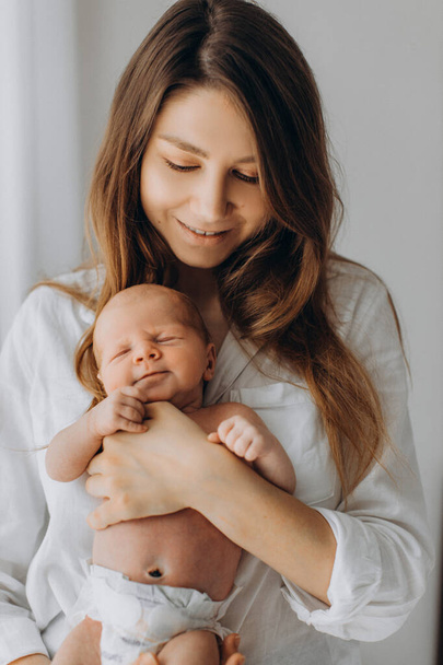 Pretty woman hold beautiful newborn baby girl in arms, happy mom enjoy tender moments with little daughter, smiling, maternity and parenting concept - Foto, Imagem